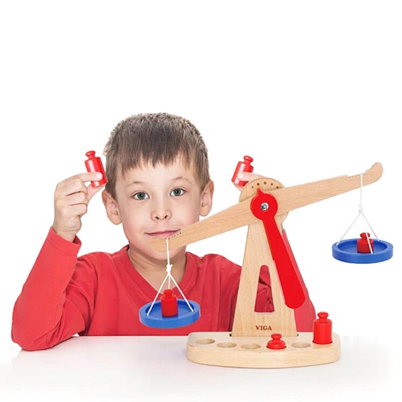 Child holding a wooden balancing scale bar; blue bowls and red weights, Viga