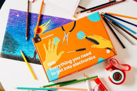 Electronics tools box surrounded by pens, pencils, and crafting materials