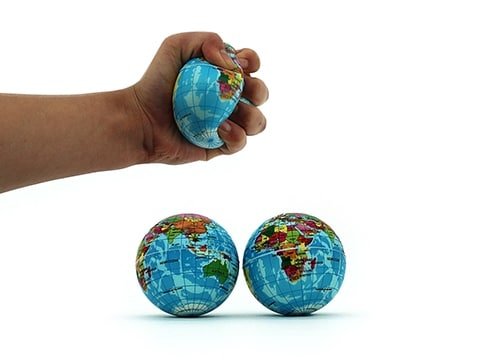 Earth-themed stress ball in blue with colorful world map, held in a hand