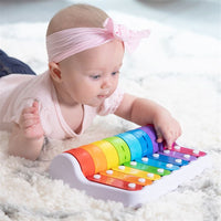 Baby hands playing a colorful roller piano toy with rainbow keys
