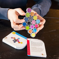 Gear-matching toy with colorful circular cogs and grey base pieces in hands