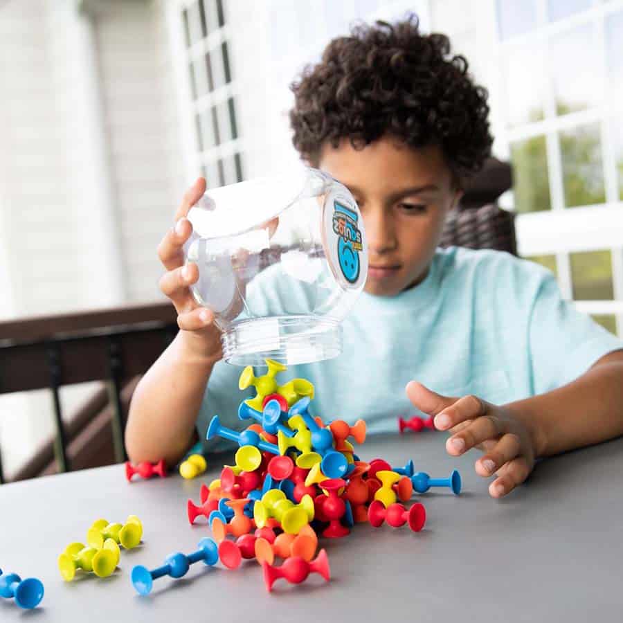 Mini Squigz suction building pieces with blue, red, and yellow parts on a tabletop