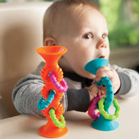 Orange loop toy with teal, pink, and green squiggle rings on pedestal
