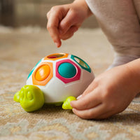 Colorful pop-and-slide turtle toy with hex openings and yellow feet