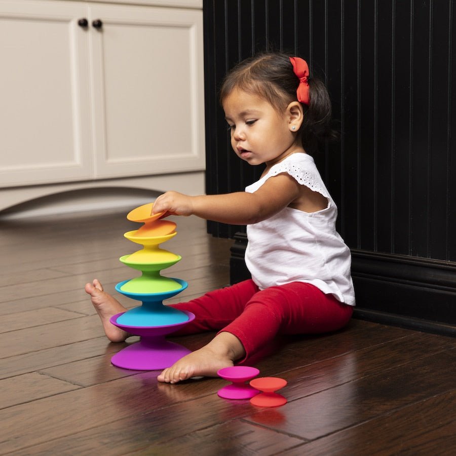Child playing with colorful stacking ring toy with interlocking discs