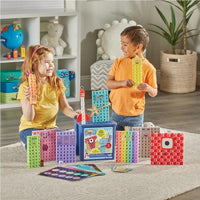 Two children holding Numberblocks-style cube characters near an open cube storage case