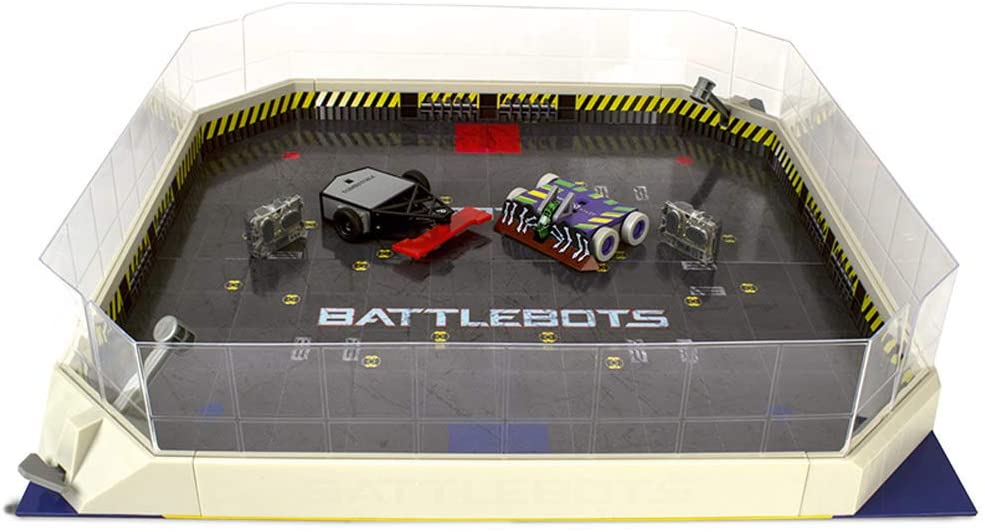 Battle arena playset view with clear walls, yellow track, and two robot toys