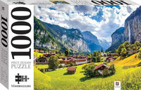 Jigsaw puzzle box showing Swiss alpine valley with village houses, green meadows, and mountains