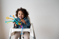 Sensory activity toy with colorful pegs and bead-like knobs on a turquoise base