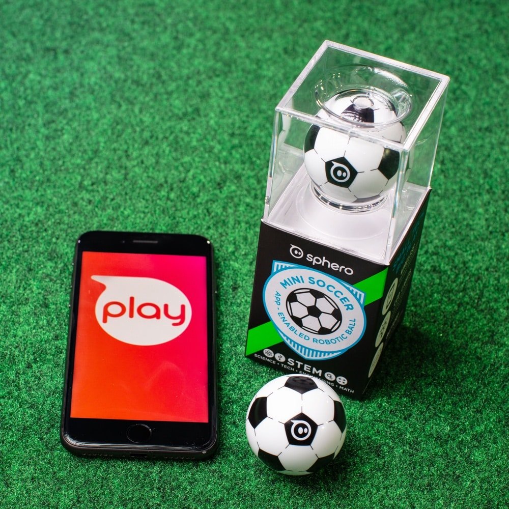 Mini soccer robot kit on grass with a ball, smartphone, and play screen
